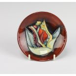 A modern Moorcroft circular dish the red ground decorated with a flower 12cm