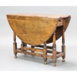 A 17th/18th Century oak oval drop flap gateleg dining table fitted a drawer raised on turned