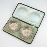 A pair of Edwardian pierced and repousse silver circular dishes decorated with cherubs, Birmingham