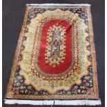 A red, gold and blue ground Persian style machine made rug with oval central medallion 259cm x 182cm