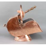 A Victorian polished copper helmet shaped coal scuttle complete with shovel