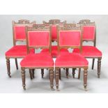 A set of five Edwardian carved oak dining chairs, the seats and backs upholstered in red material,