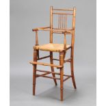 A Victorian elm stick and rail back child's high chair with woven rush seat raised on turned