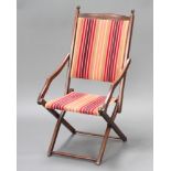 An Edwardian mahogany folding campaign armchair upholstered in striped material