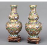 A pair of Japanese cloisonne enamelled double gourd shaped vases raised on pierced hardwood stands