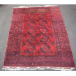 A red and black ground Afghan carpet with 10 octagons to the centre within a multi row border
