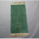 A sculpted green ground Chinese rug with blue decoration 129cm x 64cm Some staining