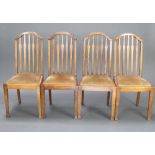 A set of 4 Edwardian oak stick and rail back dining chairs with upholstered drop in seats, raised on