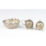 A repousse Indian silver bowl decorated with scrolling flowers 10cm, a pair of ditto condiments