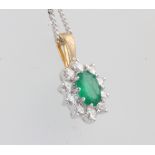 An 18ct yellow gold oval emerald and diamond cluster pendant 18mm on a silver chain, centre stone