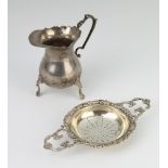 A silver 2 handled tea strainer with cast scroll rim, London 1960 together with a cream jug 202