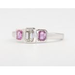An 18ct white gold emerald cut diamond and pink sapphire ring, centre diamond approx. 0.51ct flanked