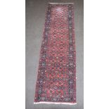 A red and blue ground floral patterned Persian runner with a 3 row border 293cm x 79cm Fringe cut in
