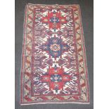 A red white and blue Afghan rug with 3 stylised medallions within a multi row border 194cm x 109cm