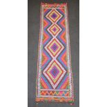 A brown, orange, purple and green ground Suzni Kilim runner with 4 stylised diamonds to the centre