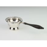 A silver tea strainer with turned wooden handle and stand, Birmingham 1984, 64 grams