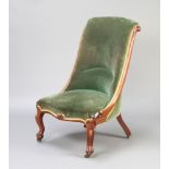 An early Victorian mahogany show frame nursing chair upholstered in green material, raised on