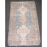 A pink and blue ground Persian rug with 3 stylised medallions to the centre within a multi row