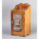 An Art Nouveau and embossed metal hanging smokers cabinet with raised back, the pressed metal door