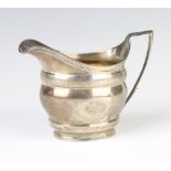 A George III cream jug with engraved decoration and vacant armorial London 1803, 164 grams