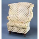 A Georgian style winged library chair upholstered in yellow material raised on turned bun feet,