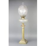 A brass oil lamp with etched glass shade, clear glass chimney and glass reservoir, raised on a brass