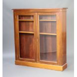 An Edwardian walnut bookcase, fitted shelves enclosed by glazed panelled doors, raised on a platform