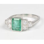 A platinum Art Deco style emerald and diamond ring, the centre cut emerald approx. 1.1ct flanked