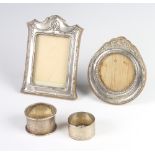 A silver napkin ring Birmingham 1933, 1 other and 2 repousse silver photograph frames Birmingham
