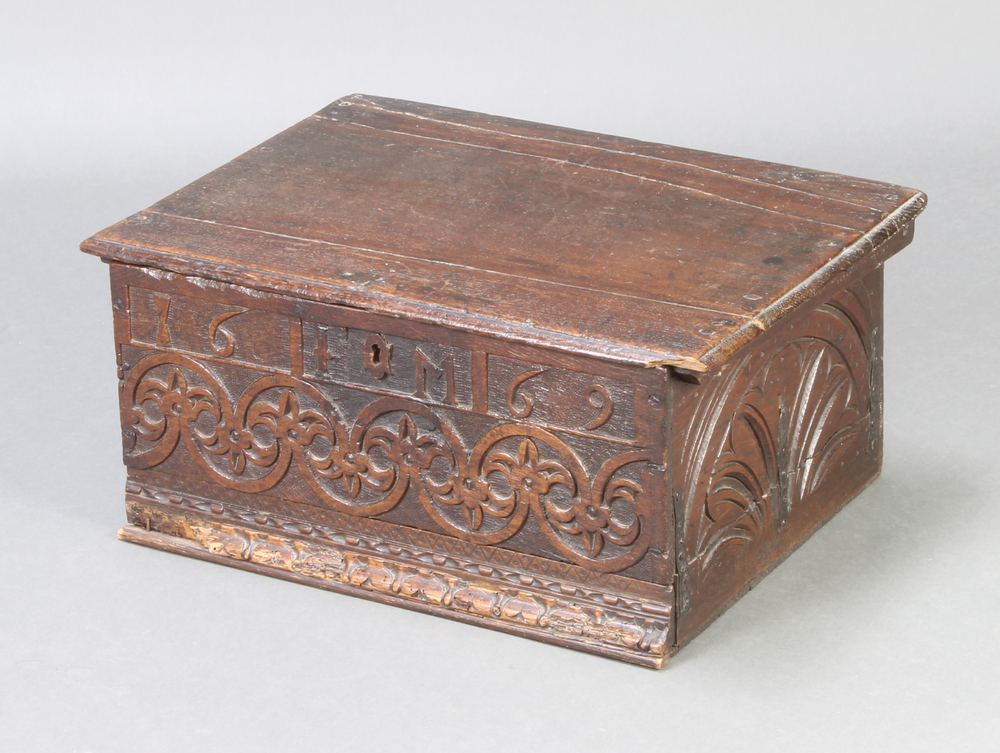 An 18th/19th Century carved oak bible box with hinged lid and iron butterfly hinges, the apron
