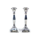 A PAIR OF GEORGE V SILVER CANDLESTICKS with square swollen stems, on square bases,