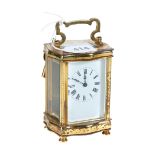 AN EARLY 20TH CENTURY FRENCH BRASS 8 DAY CARRIAGE CLOCK with white enamel dial in a serpentine