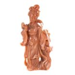 A CHINESE RUSSET HARDSTONE CARVING OF A YOUNG WOMAN standing beside a flowering vase,