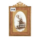 AN EARLY 20TH CENTURY RECTANGULAR GILT METAL PHOTO FRAME with foliate and ribbon crest containing a