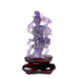 A CHINESE CARVED AMETHYST FIGURE OF GUANYIN, 3 1/2 ins high with a wooden base.