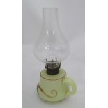 A small glass oil lamp with floral decoration, loop handle and clear glass chimney.