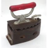 A late 19thC / early 20thC cast iron charcoal coal sad iron, with a red painted wooden handle.