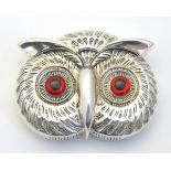 A novelty white metal vesta case formed as an owl head with glass eyes.