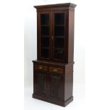 An Edwardian mahogany glazed bookcase, having a moulded cornice above two doors,