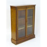 An early 20thC glazed oak bookcase with a fluted frieze and carved floral motifs above two glazed