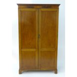 An early 20thC mahogany wardrobe with a small dentil moulded cornice and flame mahogany frieze