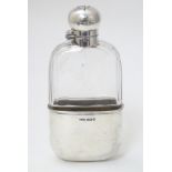 A Victorian glass hip flask with silver mounts and beaker to base.