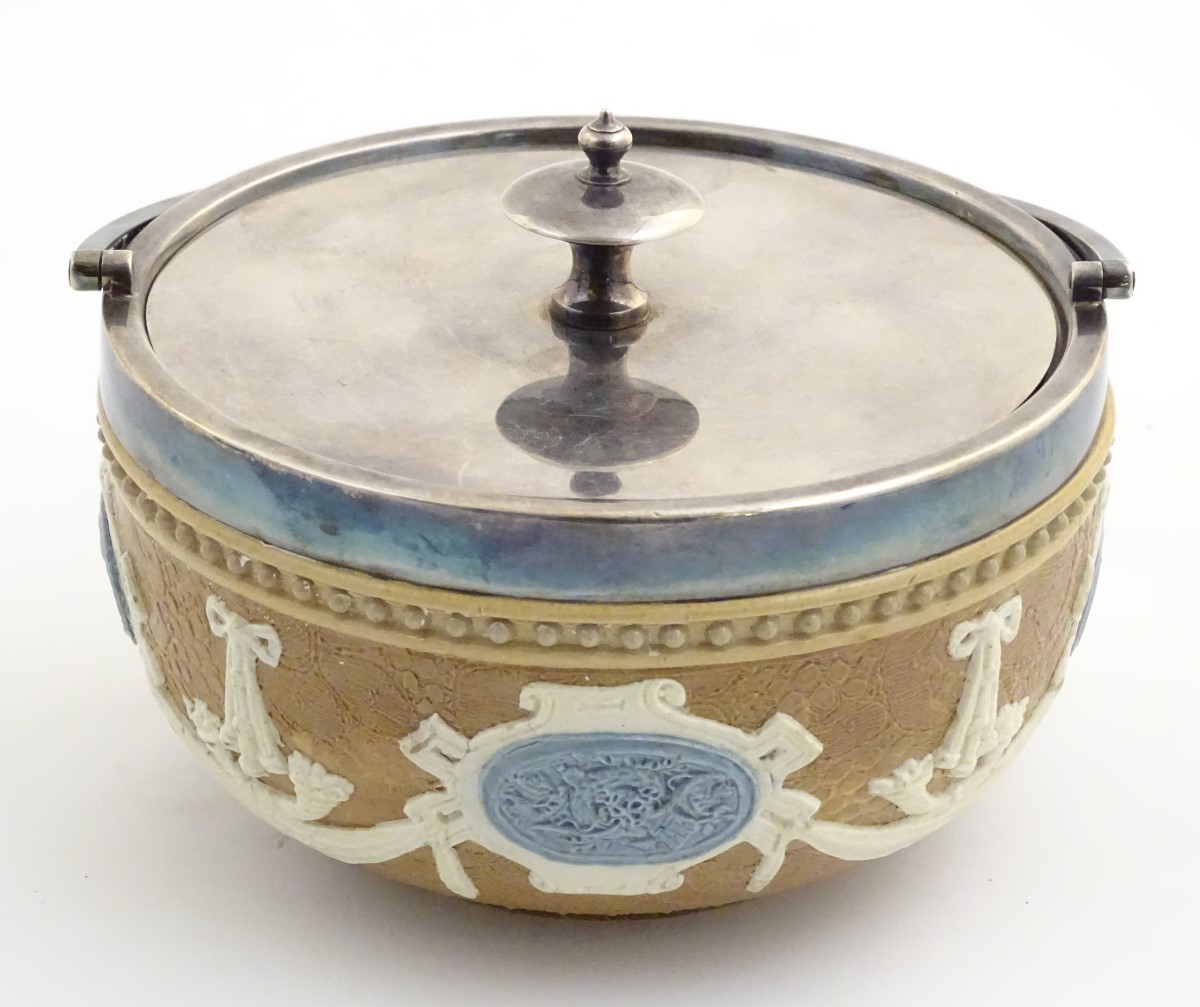 A Doulton Lambeth pot with a silver plate lid and swing handle,