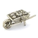 A novelty white metal pill box formed as a wheelbarrow laden with gourds.