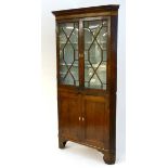 A mid / late 18thC oak corner cupboard with a moulded cornice above two astragal glazed doors