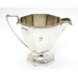 An Art Deco silver cream jug on a stepped octagonal base.
