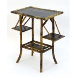 An early / mid 20thC folding bamboo table with a black lacquered top and two painted under tiers,