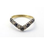 A silver gilt ring set with white and black stones in a wishbone setting.