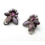 A pair of white metal clip earrings set with various purple stones.