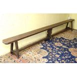 An early 20thC pine bench with three supports and a straight stretcher.